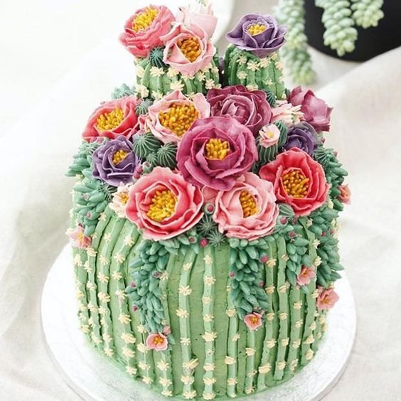 cake covered with butter cream and transformed into a cactus decorated with red flowers