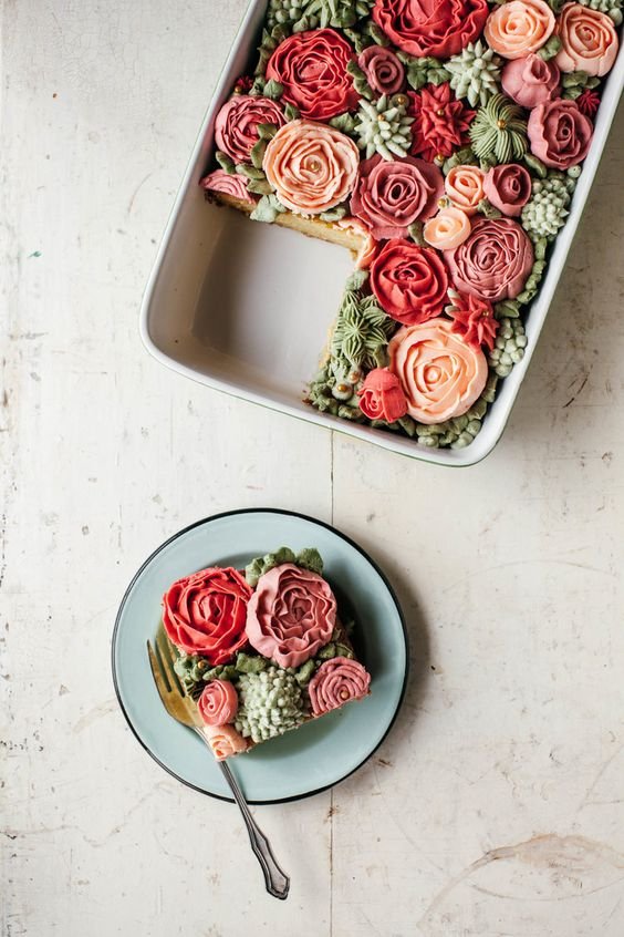 rectangular cake in oven dish covered with roses and succulents in butter cream
