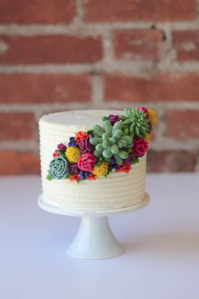 white layered cake with succulents and colorful flowers