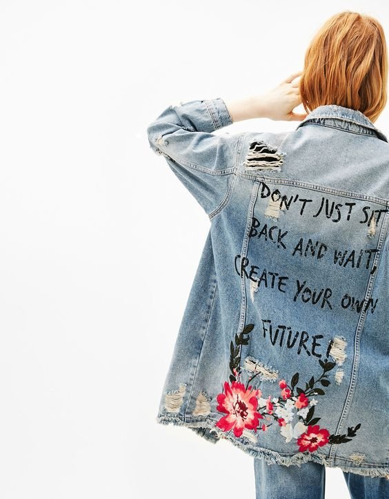 Loose denim jacket, worn effect with a message written with a black brush and flowers in embroidery