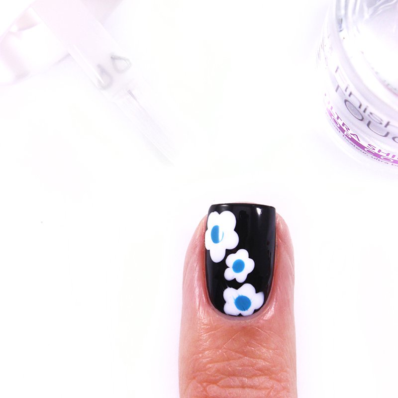 small white flowers with blue heart on nail varnish in black