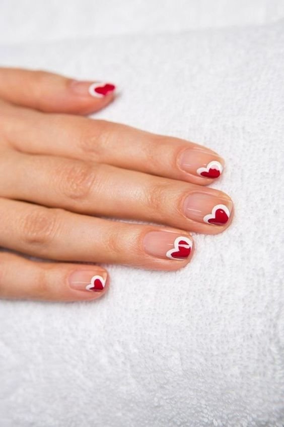red hearts surrounded by white on the tip of the nail