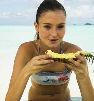 Flat belly, young woman on the beach eating a pineapple, excellent for the line
